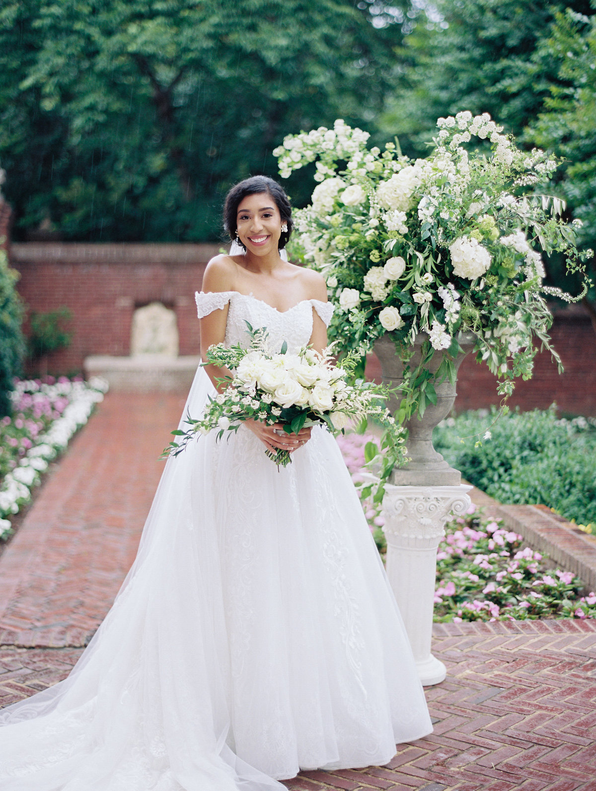 Bride with white bouquet in front of a large arrangement with white flowers