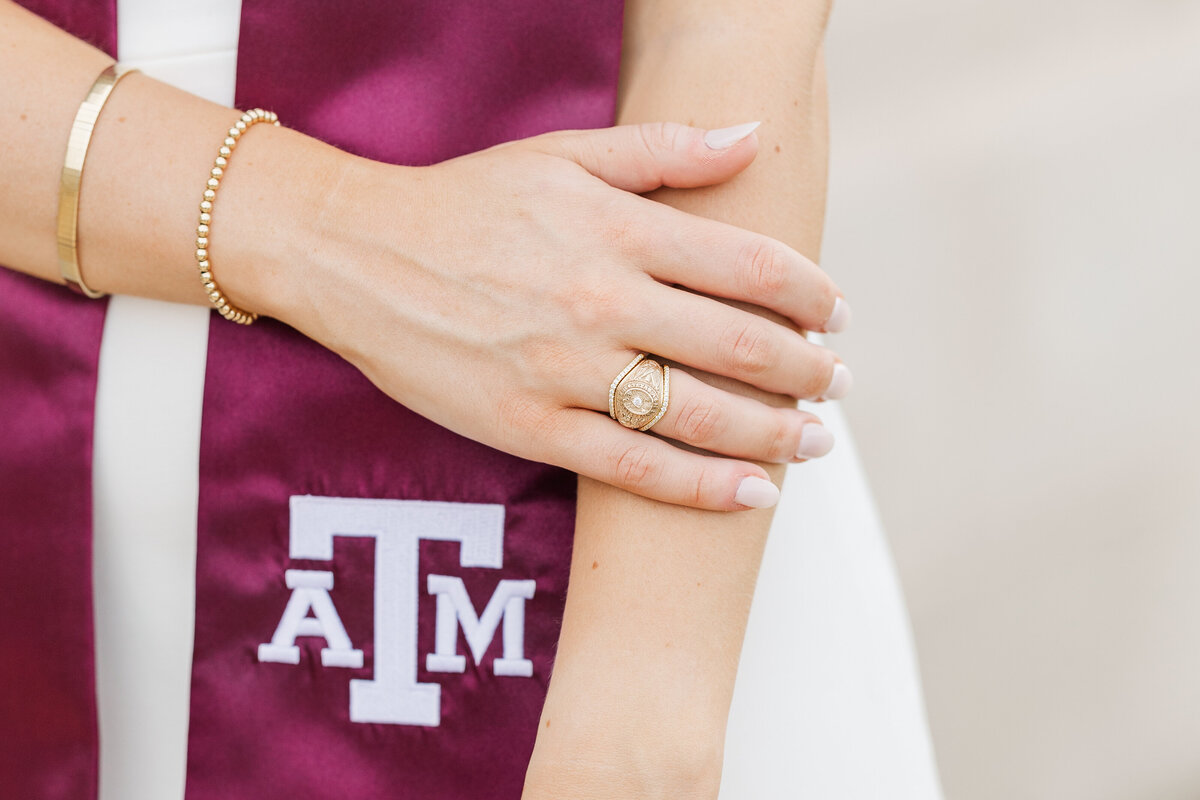 A close-up image featuring a gold Texas A&M Aggie ring and maroon graduation stole, symbolizing academic achievement and school pride. Captured in College Station by Jennifer Lynn Photography.