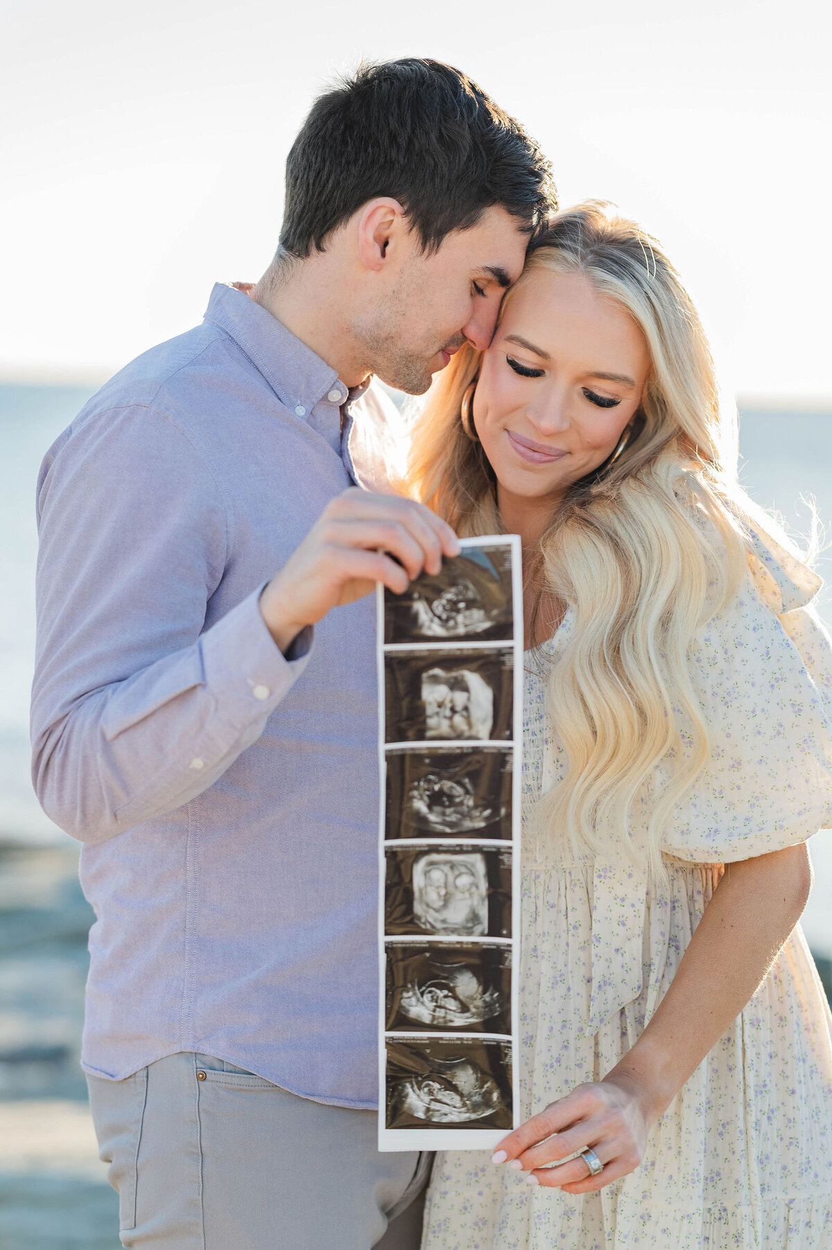 Best newborn announcement photographer image of mom and dad holding sonogram