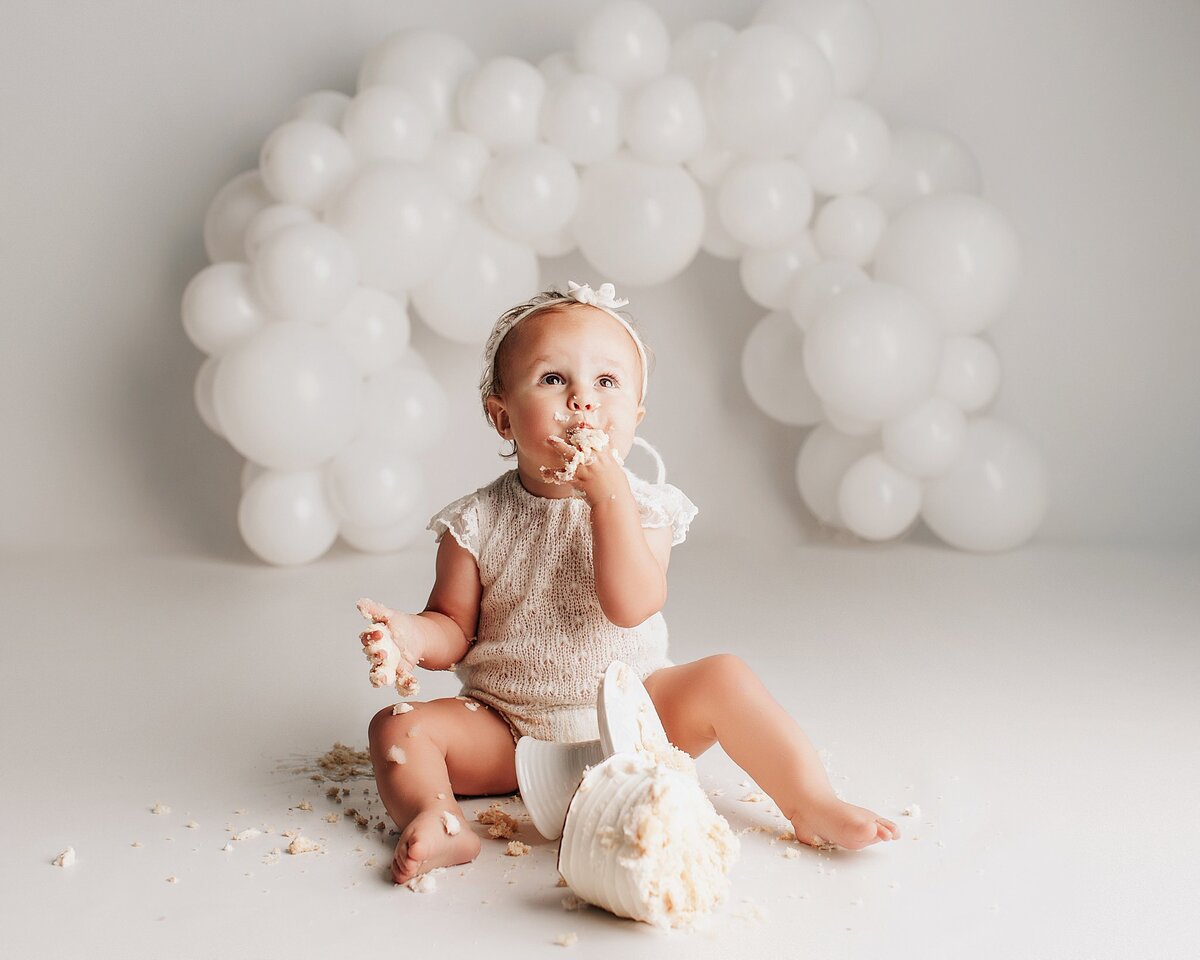 Baby reaching toward cake during first birthday photo session