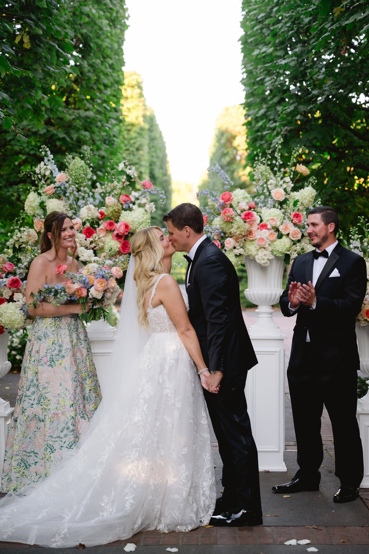 Bride and groom kissing at the altar with bridesmaids watching at the Chicago Botanic Gardens.