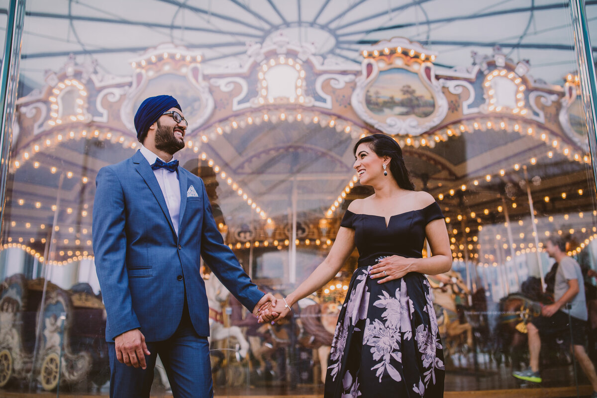 An engaged couple standing in front of the carousel at the brooklyn bridge park in dumbo during their engagement session