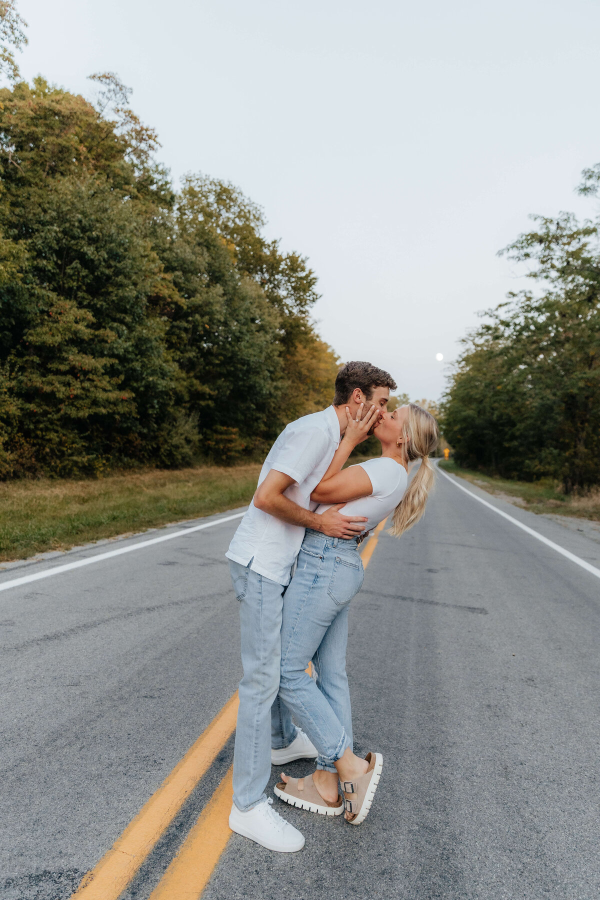 Joyful couple kissing in the road at golden hour, romantic and nostalgic Ohio engagement photos for modern, sentimental Midwest couples