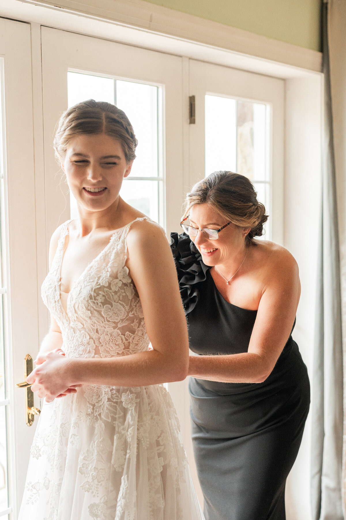 A person helping a bride zip up their wedding dress