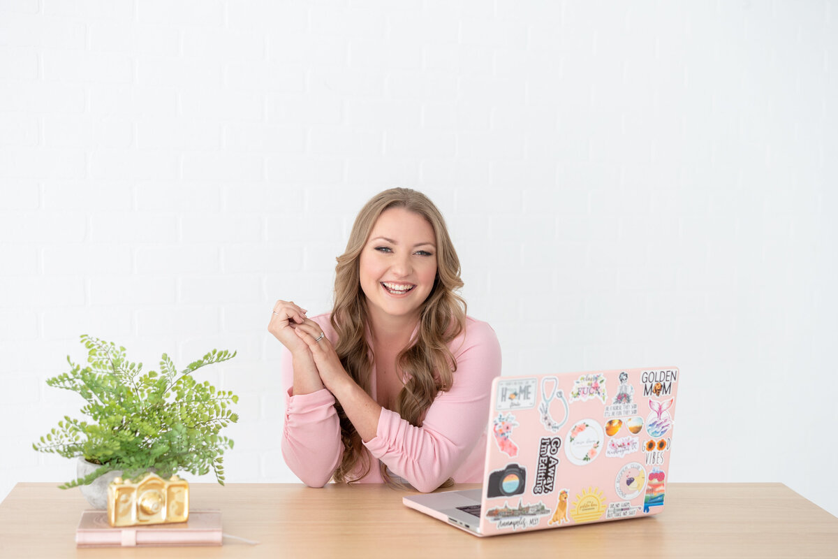 DC photographer smiling at camera with laptop