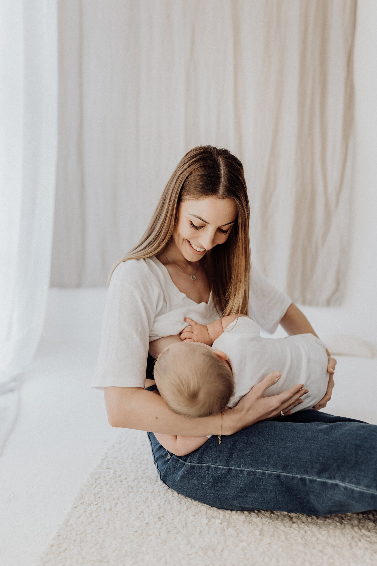 A mother breastfeeding her baby while photographed in a breastfeeding safe photography studio in christchurch