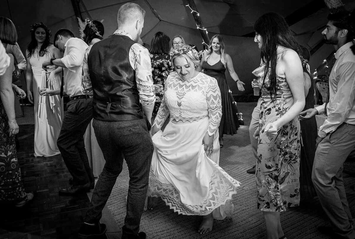 Bride swings her skirt to music and groom dances, guests all around dancing