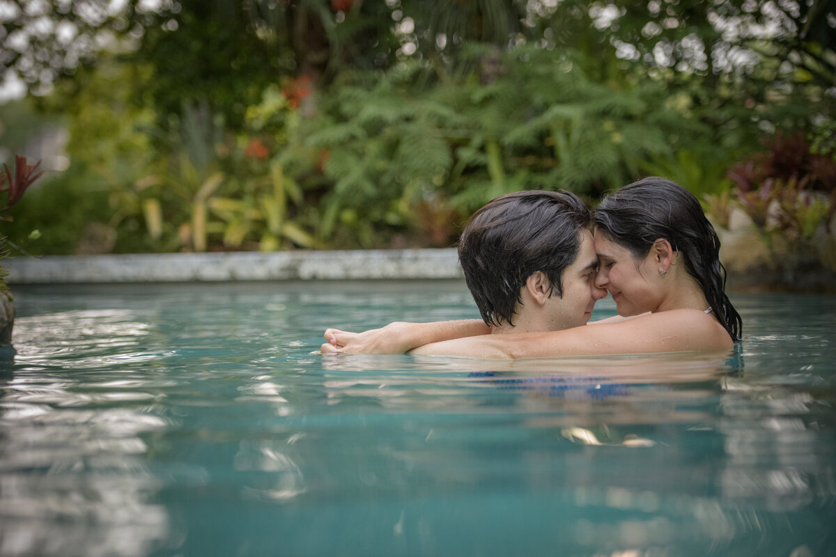 A couple shares a quiet moment together in a tropical pool setting.
