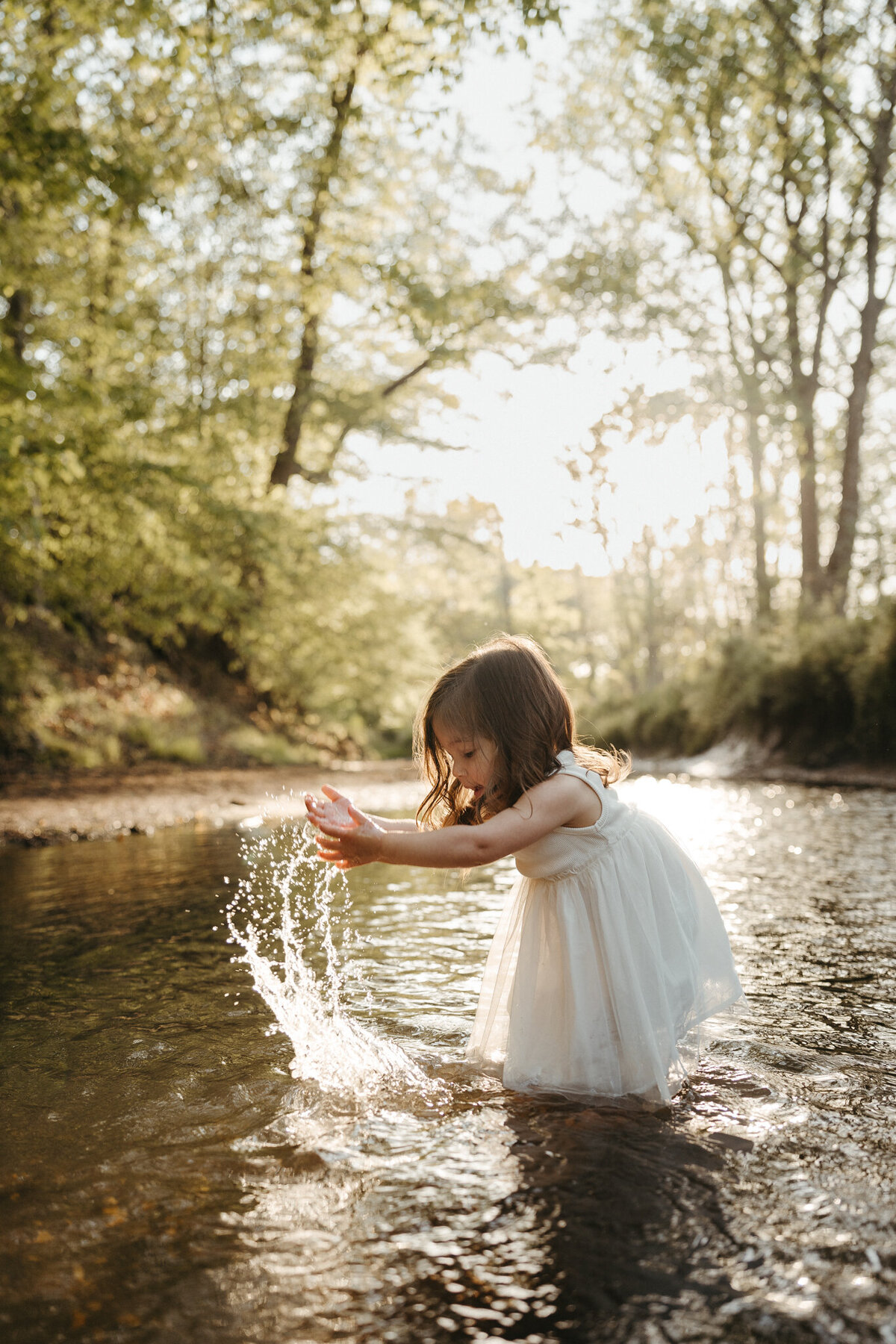Toddler girl splashing in a stream