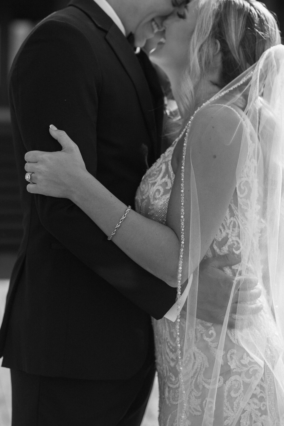 A timeless black and white close-up of a bride and groom embracing on their wedding day at the Lightner Museum in St. Augustine, Florida. The bride’s beaded veil, lace gown, and delicate bracelet are captured in beautiful contrast as she wraps her arms around the groom. Photographed by Phavy Photography in a candid, documentary style that highlights emotion, texture, and the elegance of historic St. Augustine weddings.