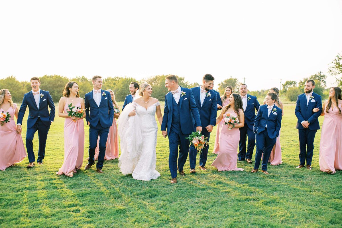 Joyful bridal party walks through meadow at Dallas Fort Worth wedding