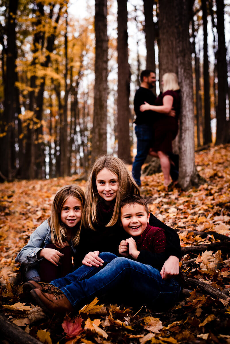 Happy siblings and cuddling parents posing for Toronto family photograhper