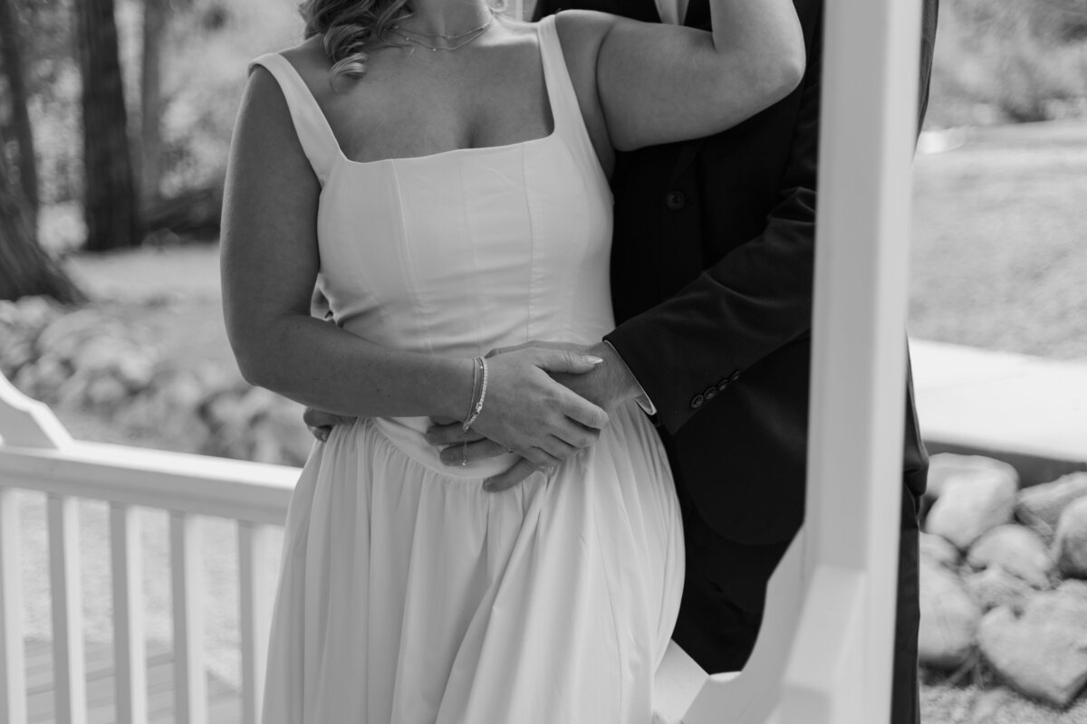 Bride leaning on groom, leaning on a banister, in black and white.
