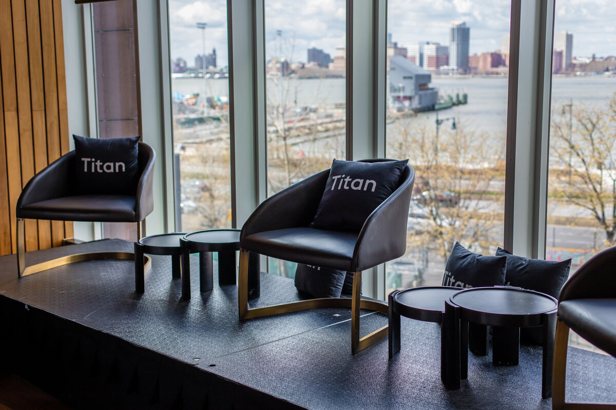 Modern stage setup with Titan-branded chairs and pillows overlooking the New York skyline.