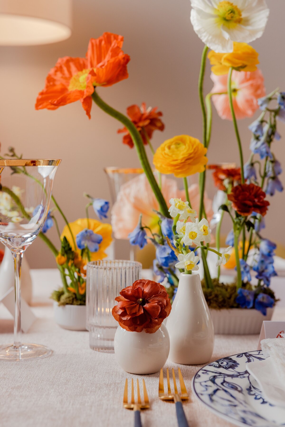 Close-up of orange and yellow ranunculus flowers in a bright, modern floral centerpiece