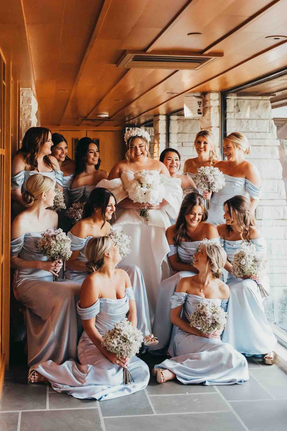 bridal party adores the bride, standing in a small hall in a church in houston.