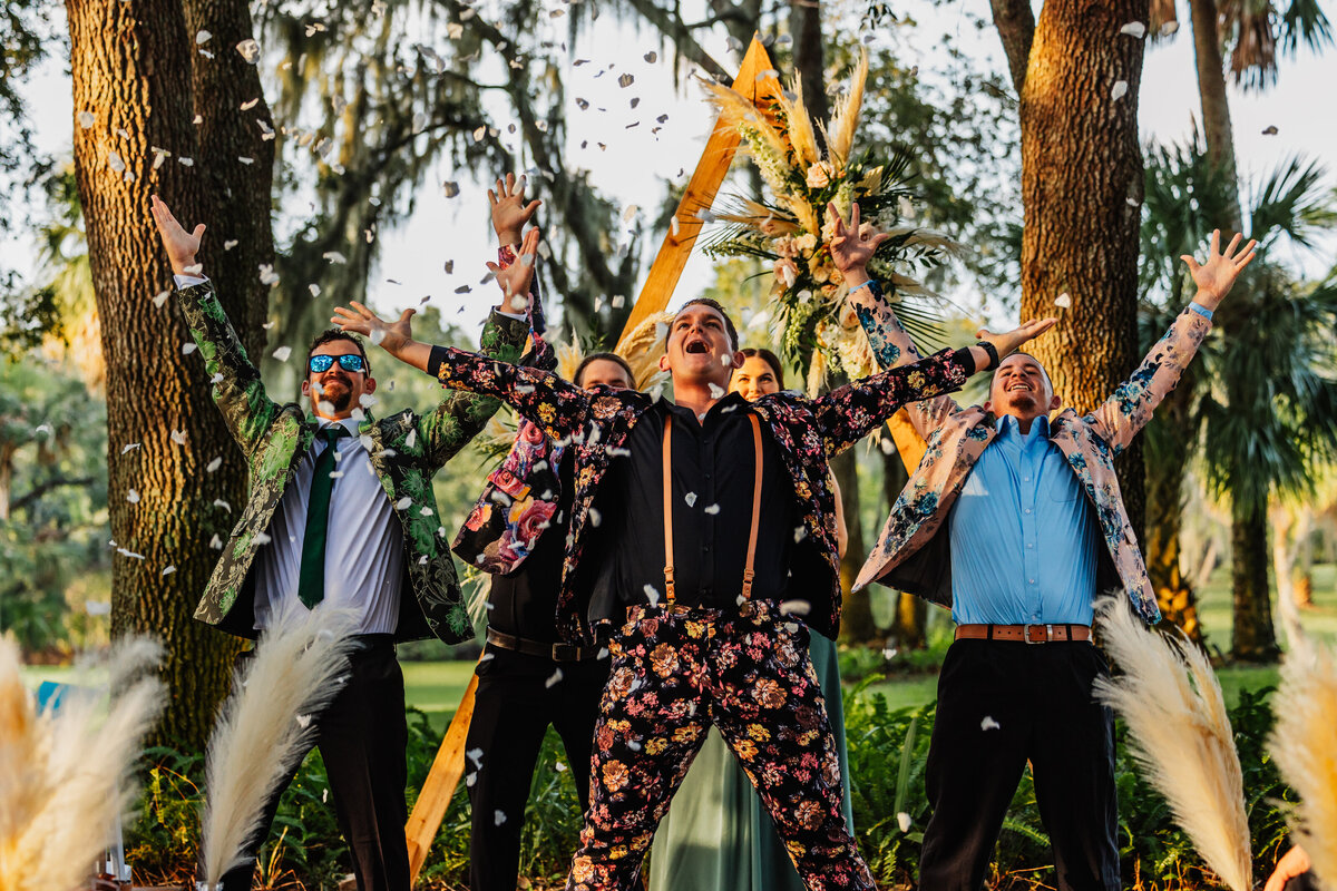 Shannon Lee, from Love Like Wild Photography, captures a joyful group of groomsmen celebrating with arms raised and confetti in the air.