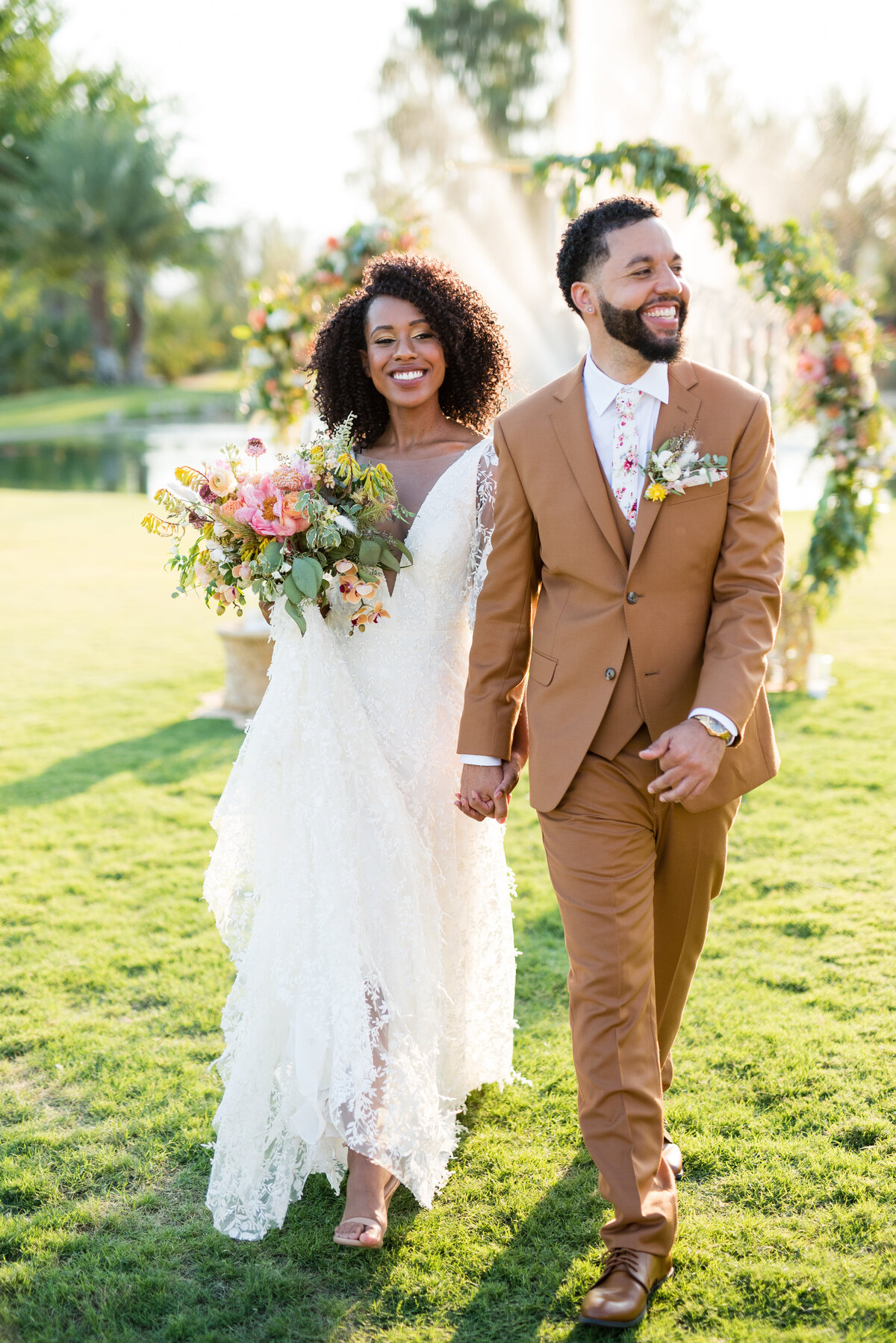Bride and groom walking hand in hand at golden hour on the grounds of the Old Polo Estate in Coachella, California.