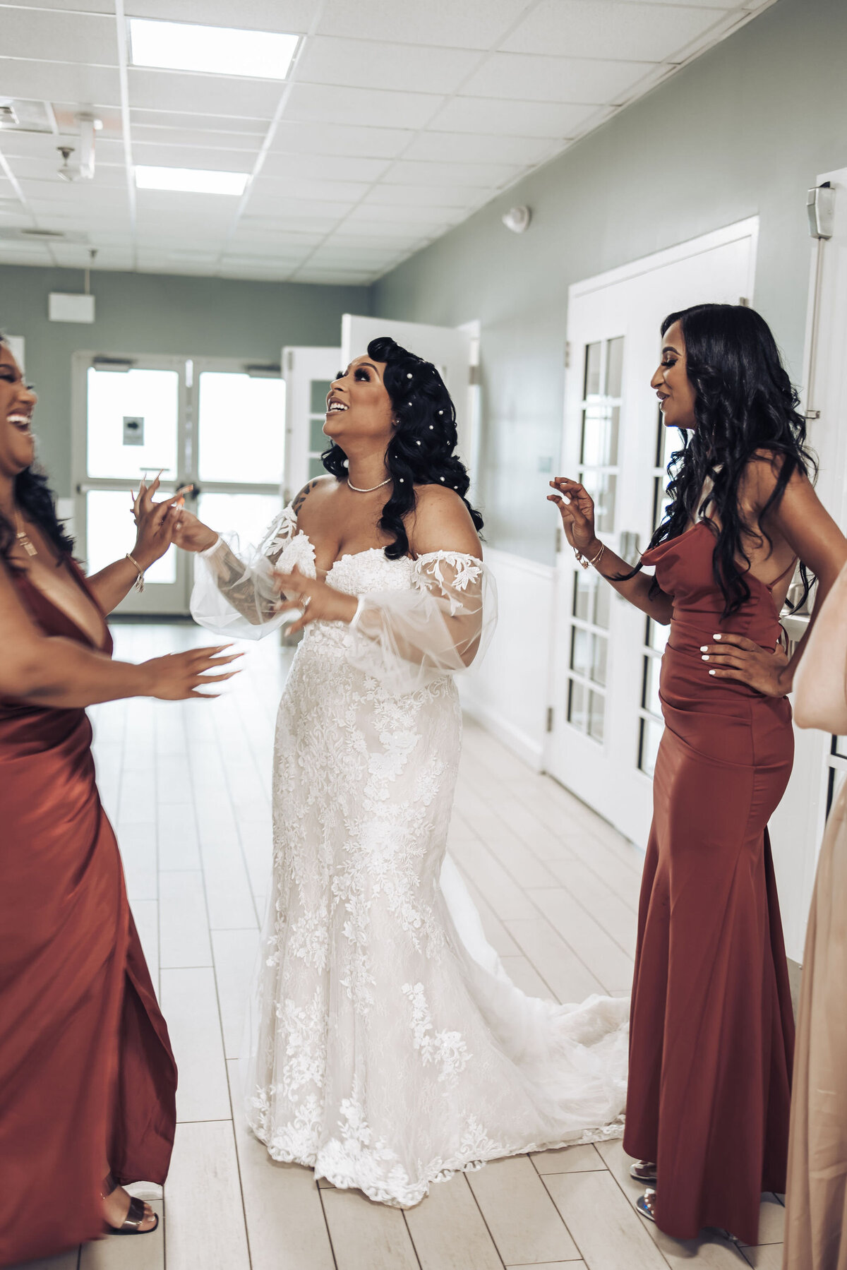 a bride in a wedding dress talking with her bridesmaids who are wearing wine colored dresses