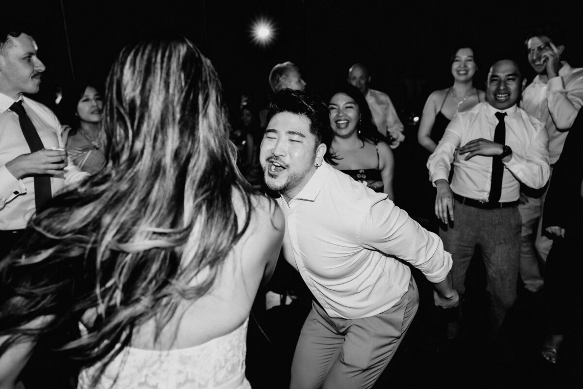 Wedding reception guest dancing excitedly in black and white