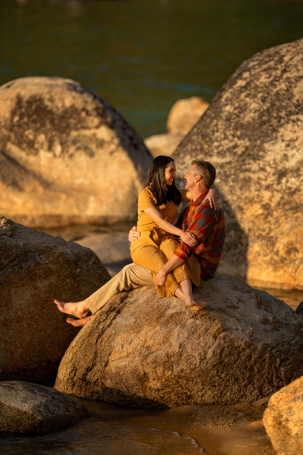 man and woman sitting on a rock by the lake at Sand Harbor beach