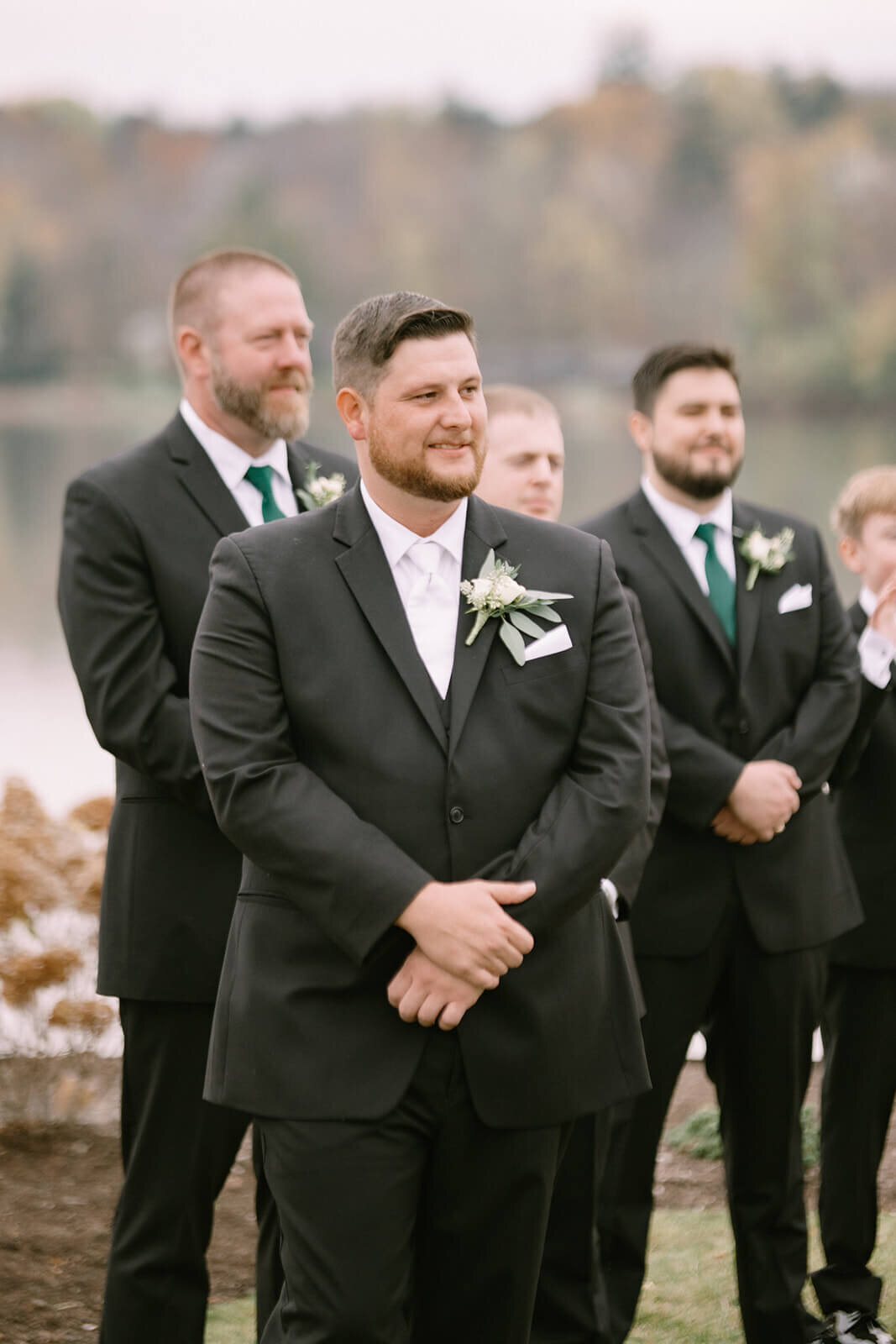 Groom with groomsmen wearing black suits looking  out in the distance