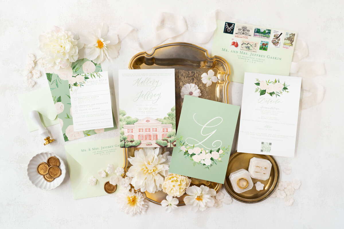 Flatlay of sage green wedding invitations for a Tate House bride in Tate, Georgia, featuring watercolor details and hand-lettered calligraphy