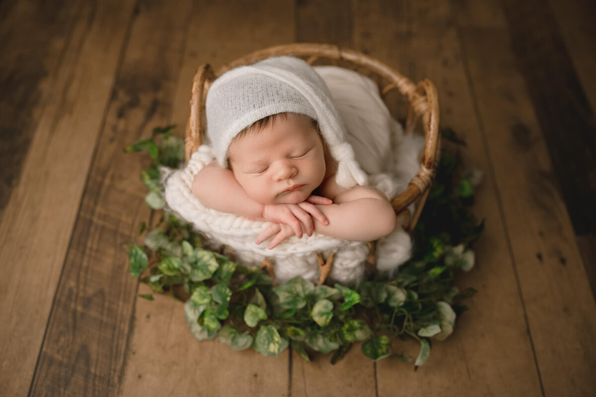 baby boy wearing white sleepy hat posed in bamboo basket, hamilton newborn photography