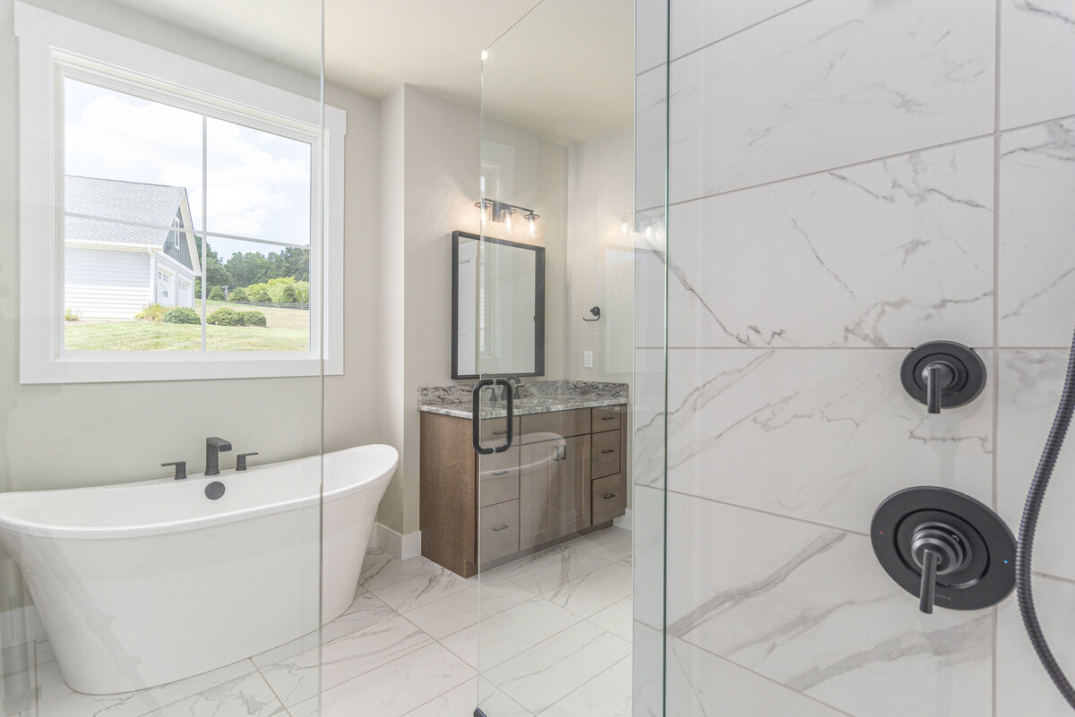 New construction bathroom in Asheville featuring marble counter tops and a walk-in shower