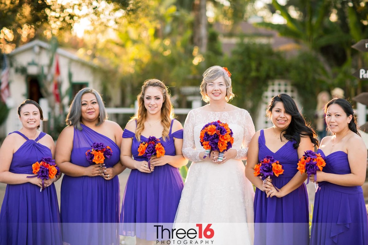 Bride poses with her Bridesmaids while holding their bouquets