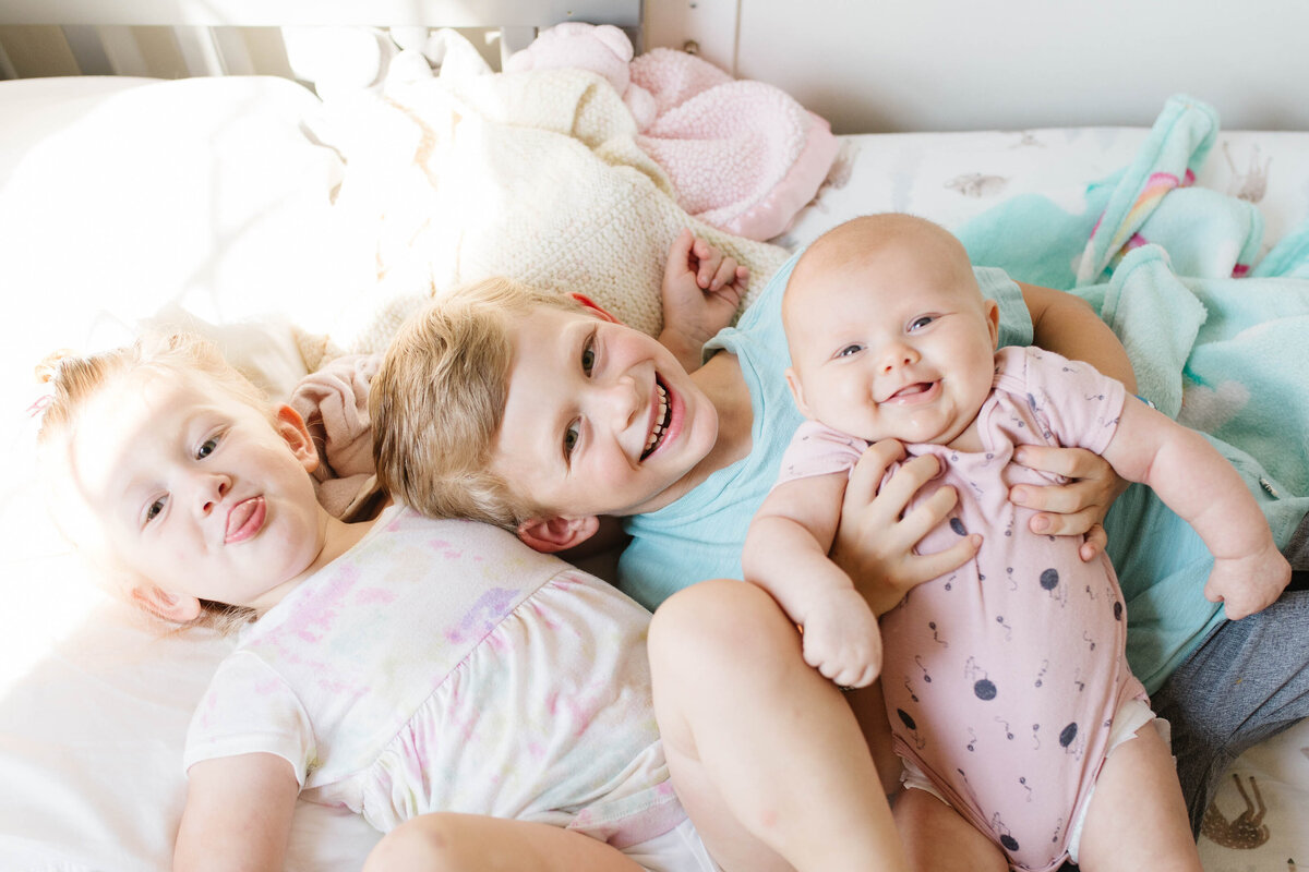 Three children laying on bed smiling