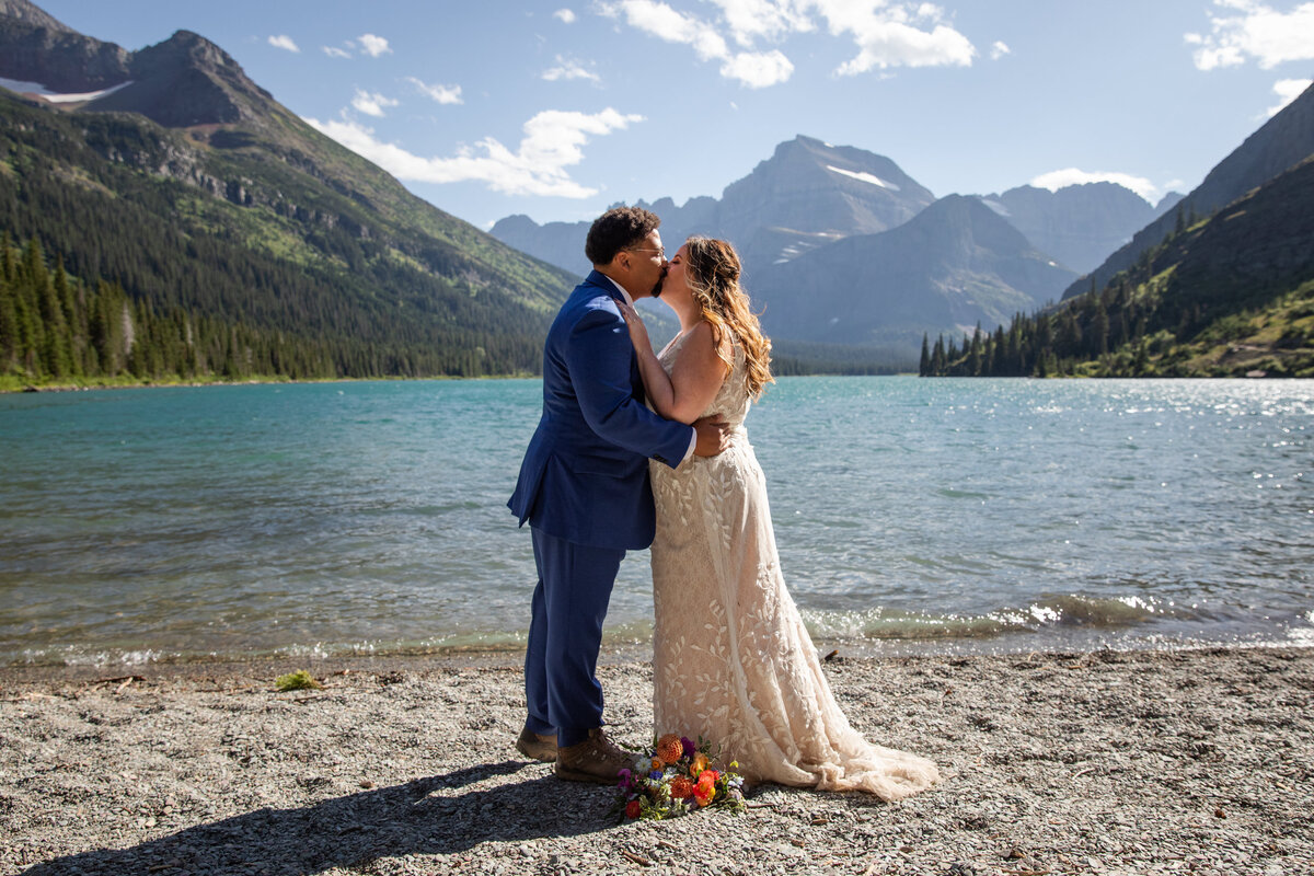 A bride and groom share their first kiss next to a lake in montana.