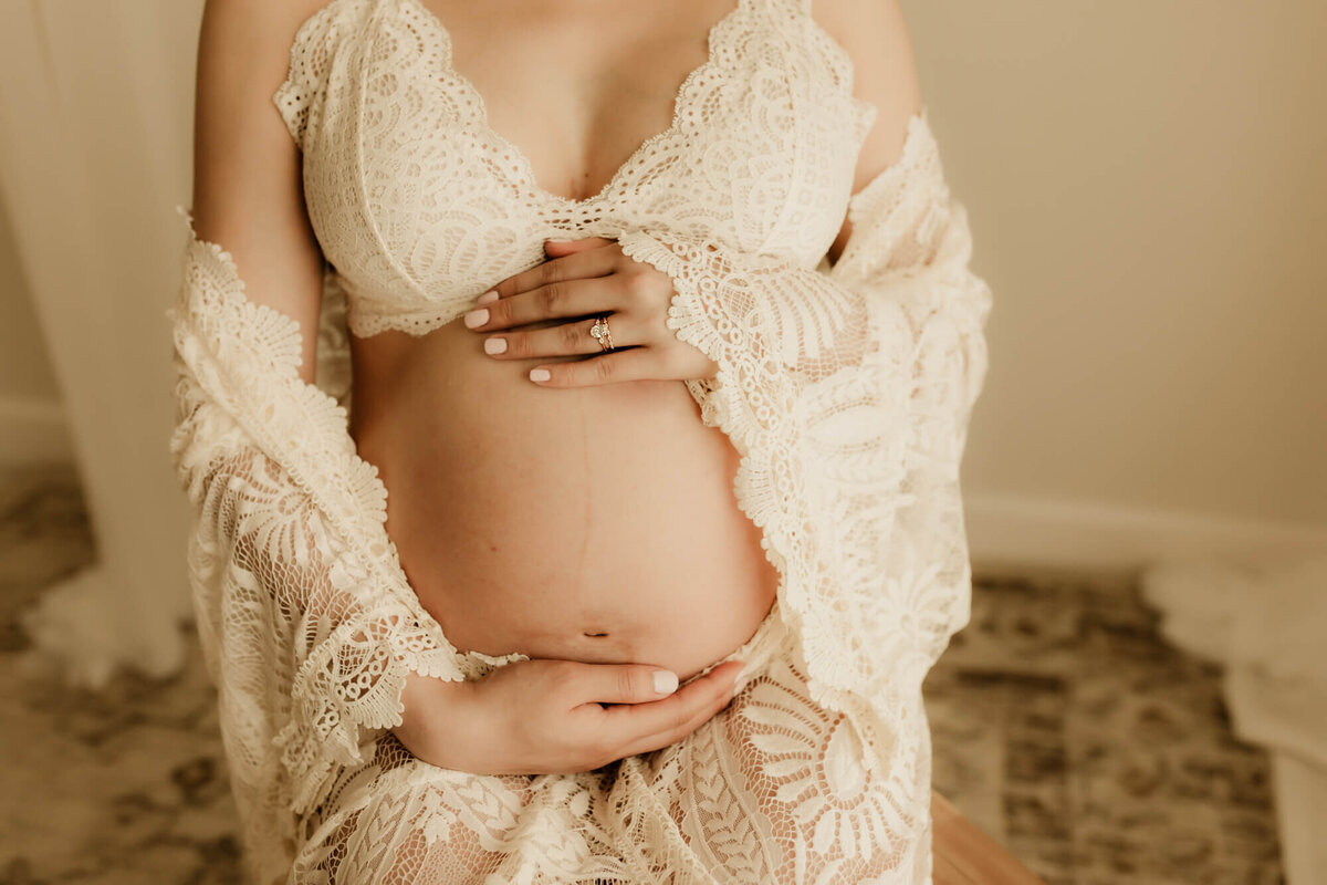 Baby bump portrait of an expecting mother wearing a cream brawlette and lace layer.
