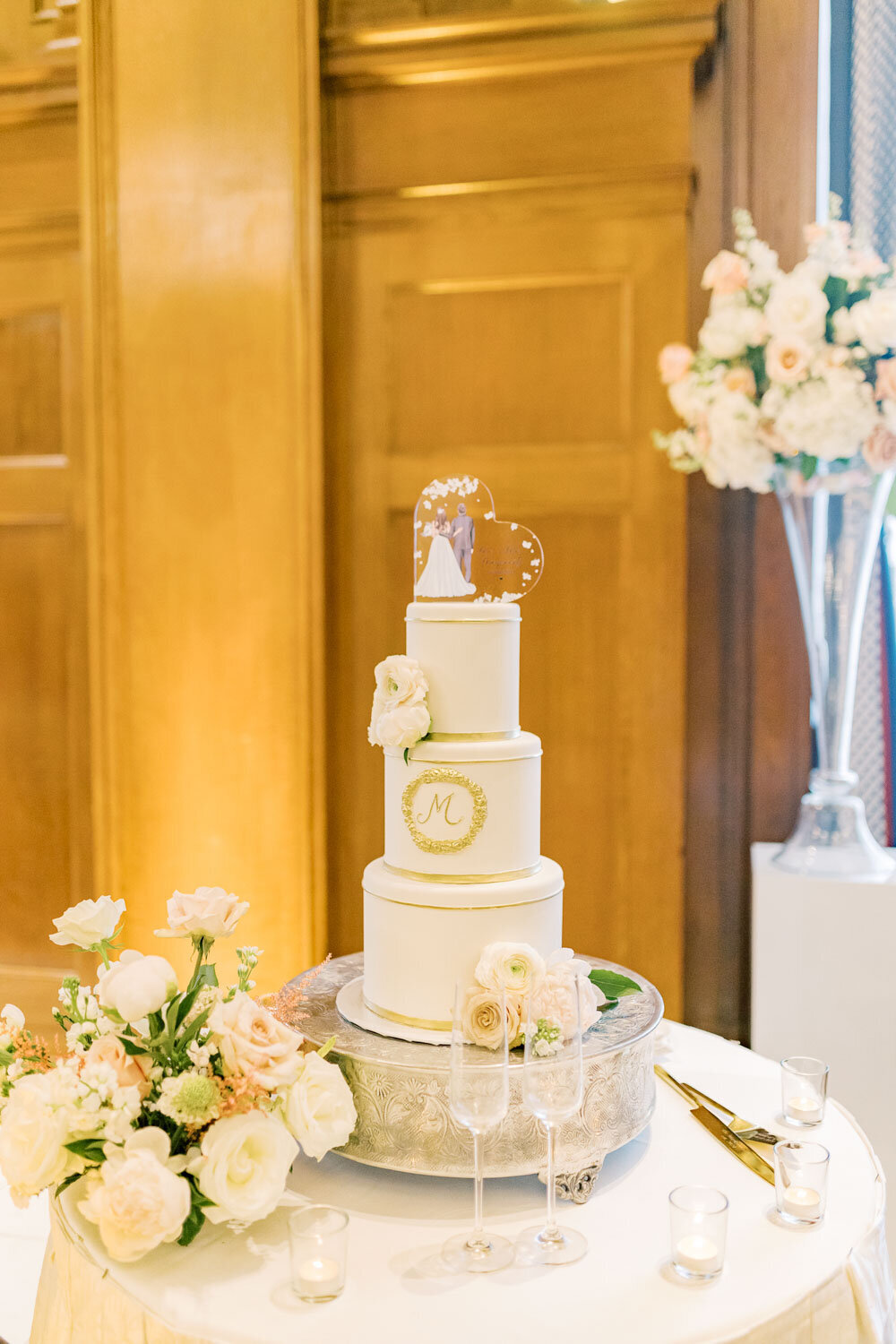 Three-tier white and gold wedding cake with floral decor