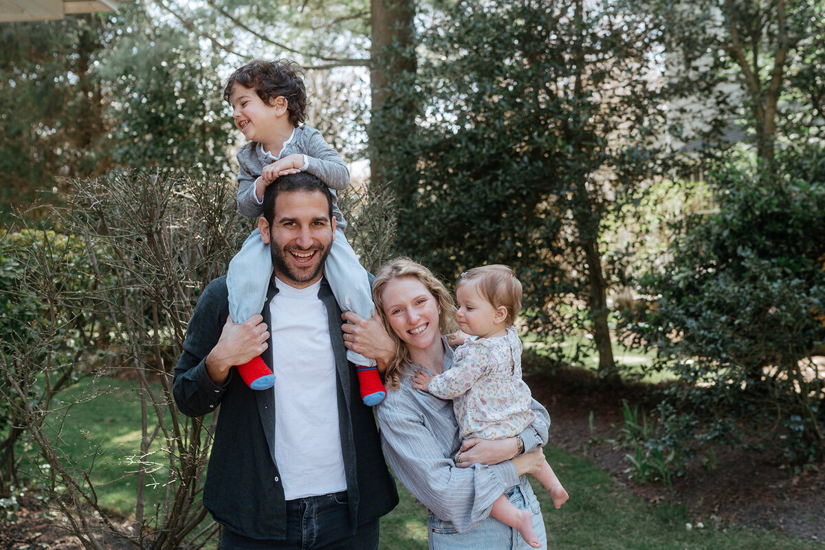 couple smiling holding two kids during family photos captured by NYC family photographer Elsie Goodman 