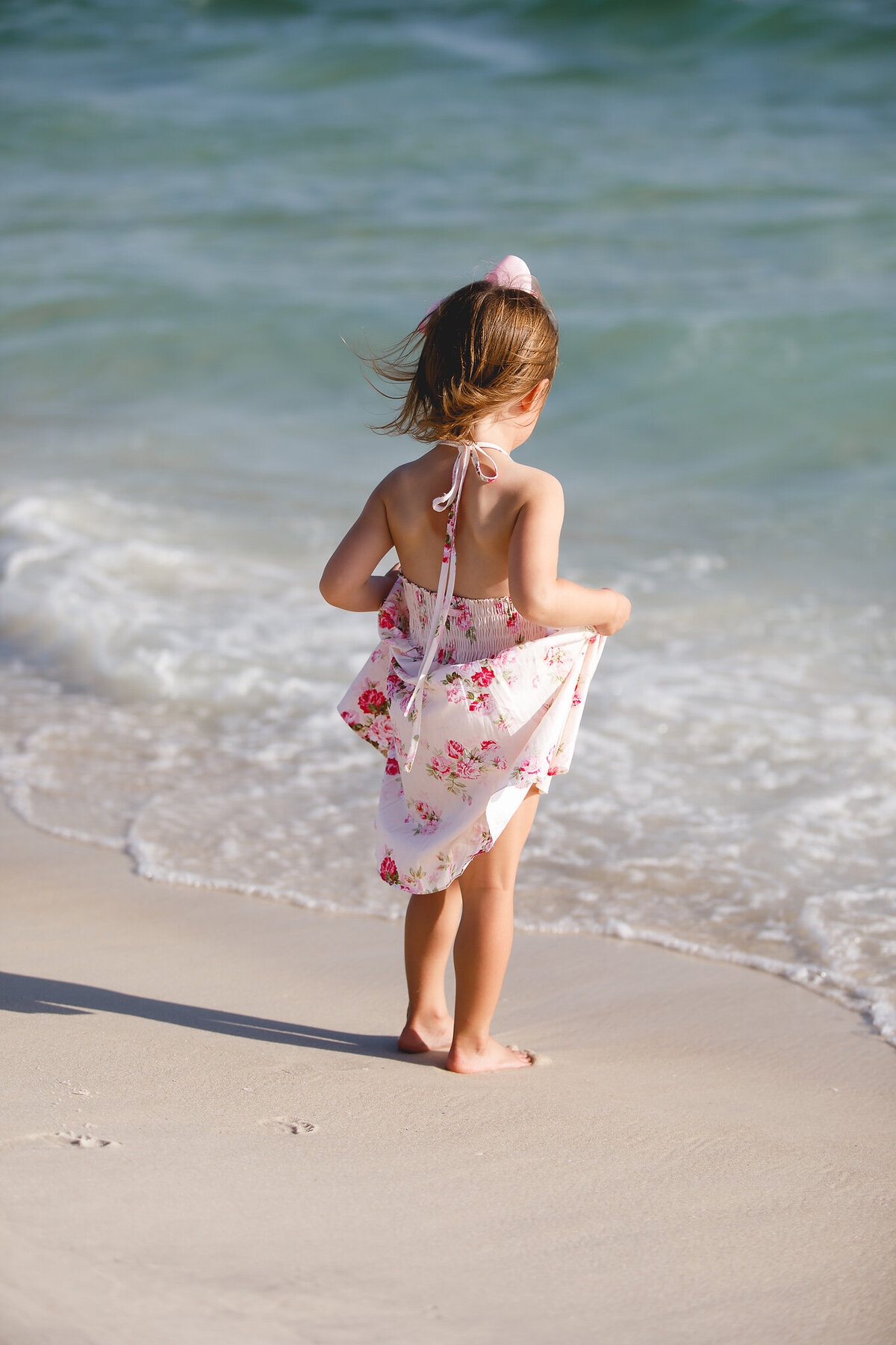 little girl on beach holding dress up