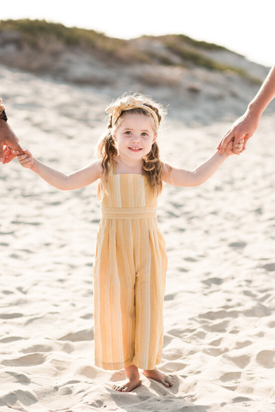 young-girl-holding-parents'-hands-Coronado-beach-san-diego