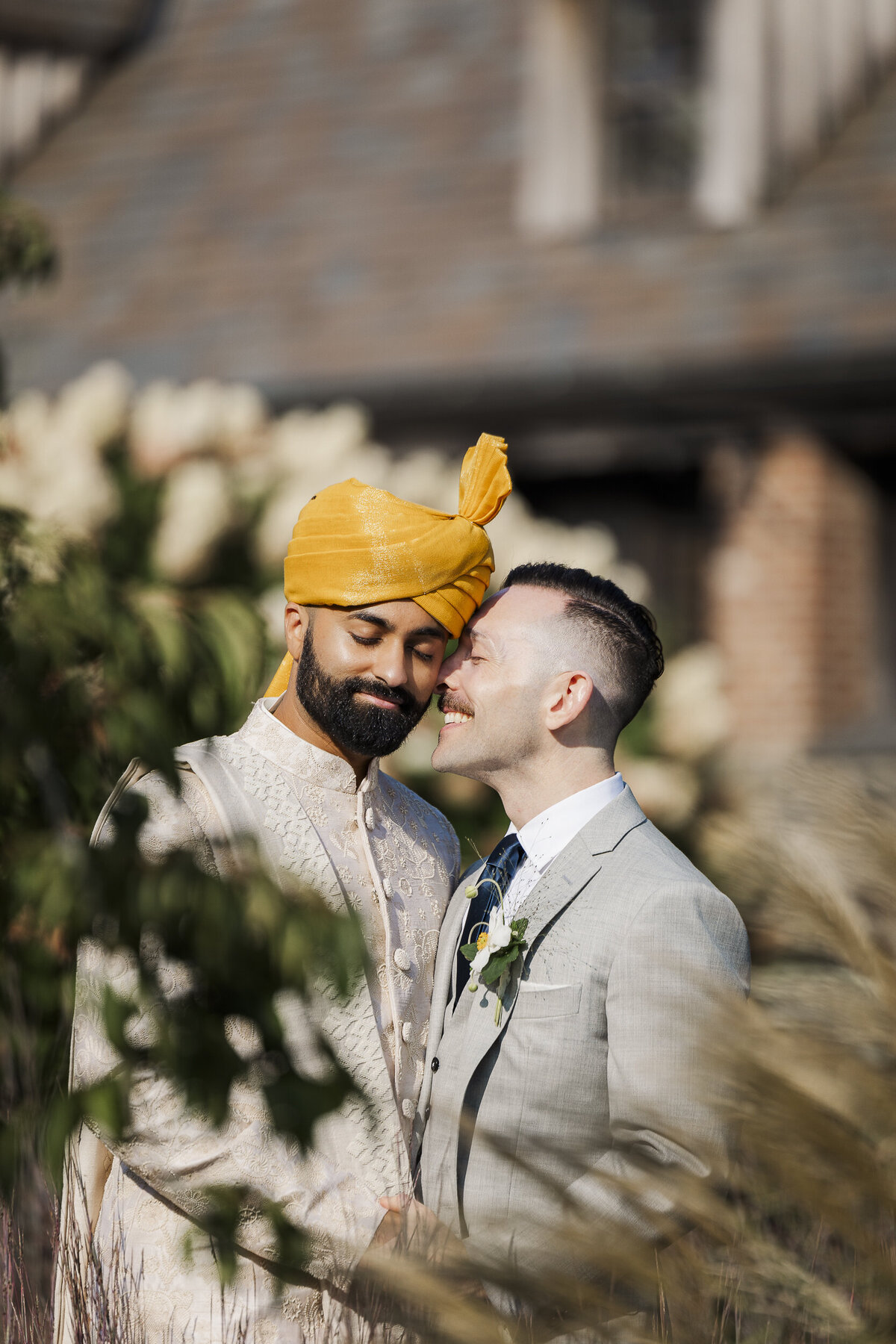 Candid Hudson Valley wedding portrait of two grooms sharing a quiet moment in golden light