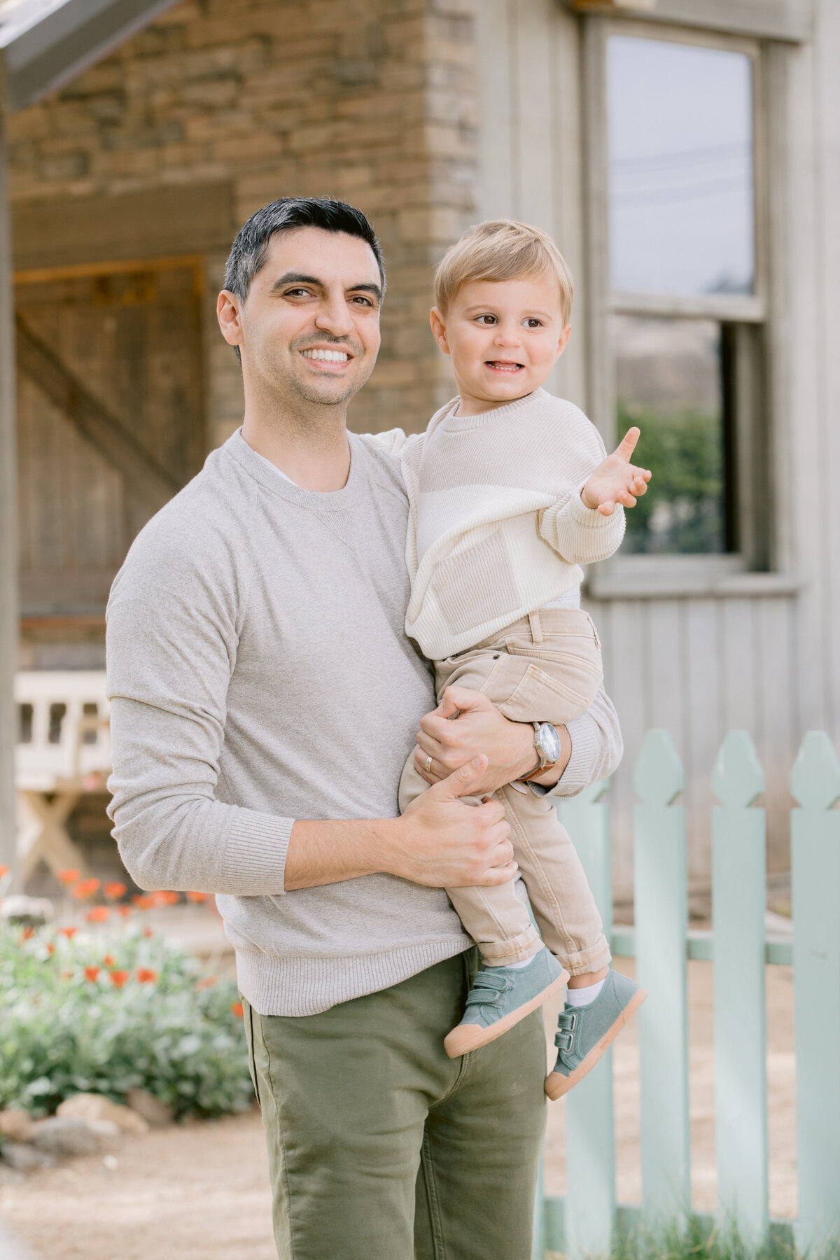 A dad holding a toddler and smiling