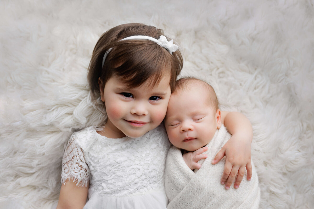 newborn baby being held by his big sister at a newborn phohoshoot