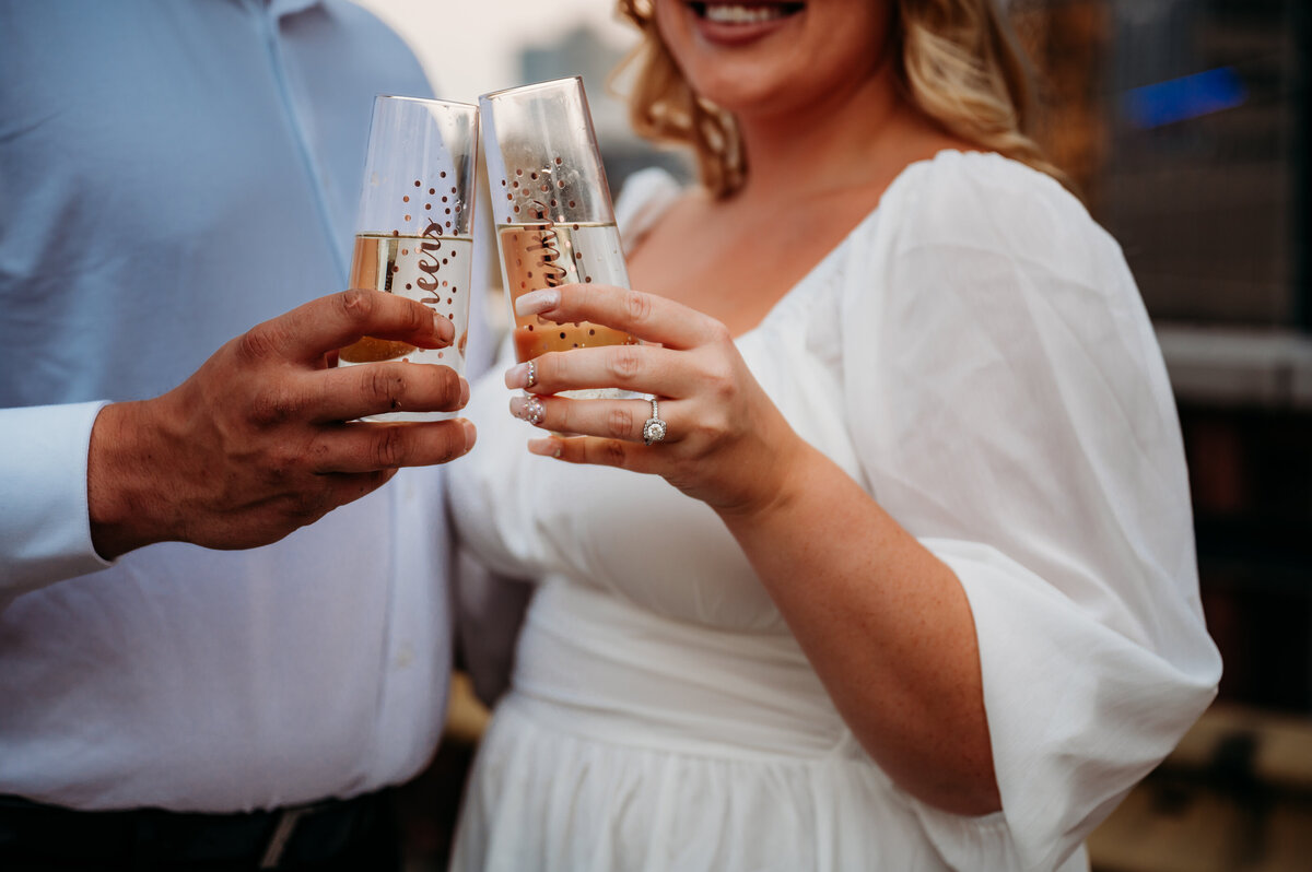 Engaged couple hold champagne classes and cheers to their engagement