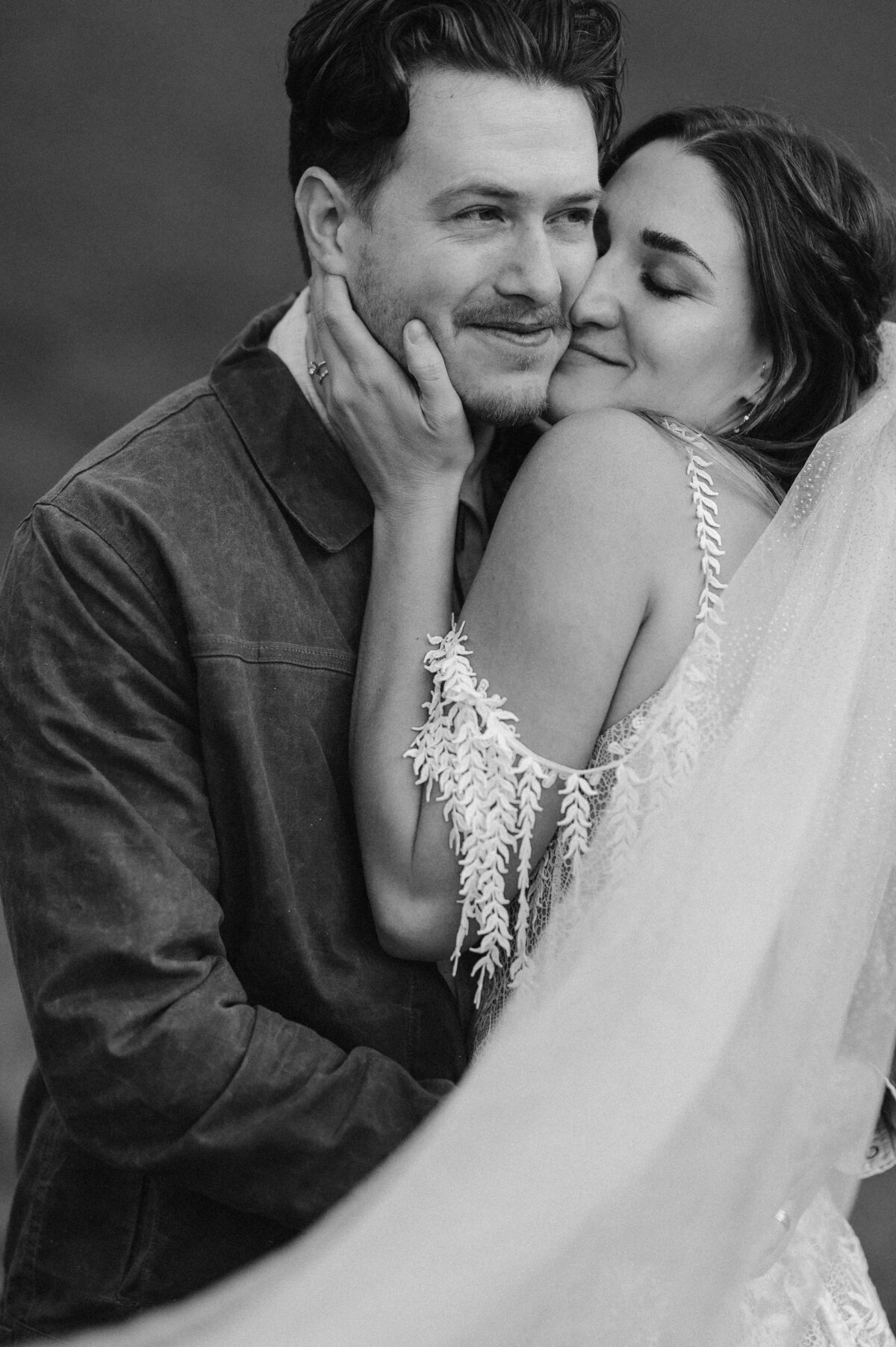 Bride embracing her groom, wearing a lace gown and long veil