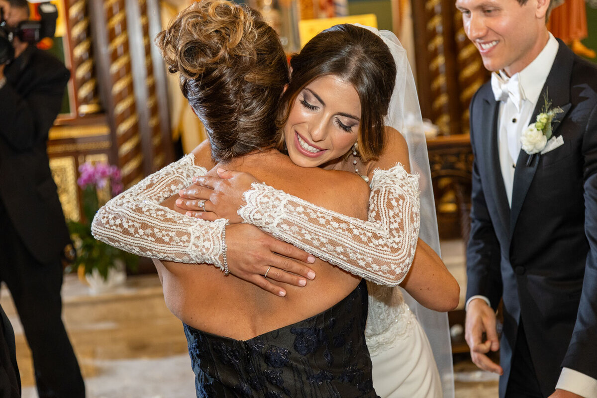 A woman in a black dress is hugging another woman in a white dress