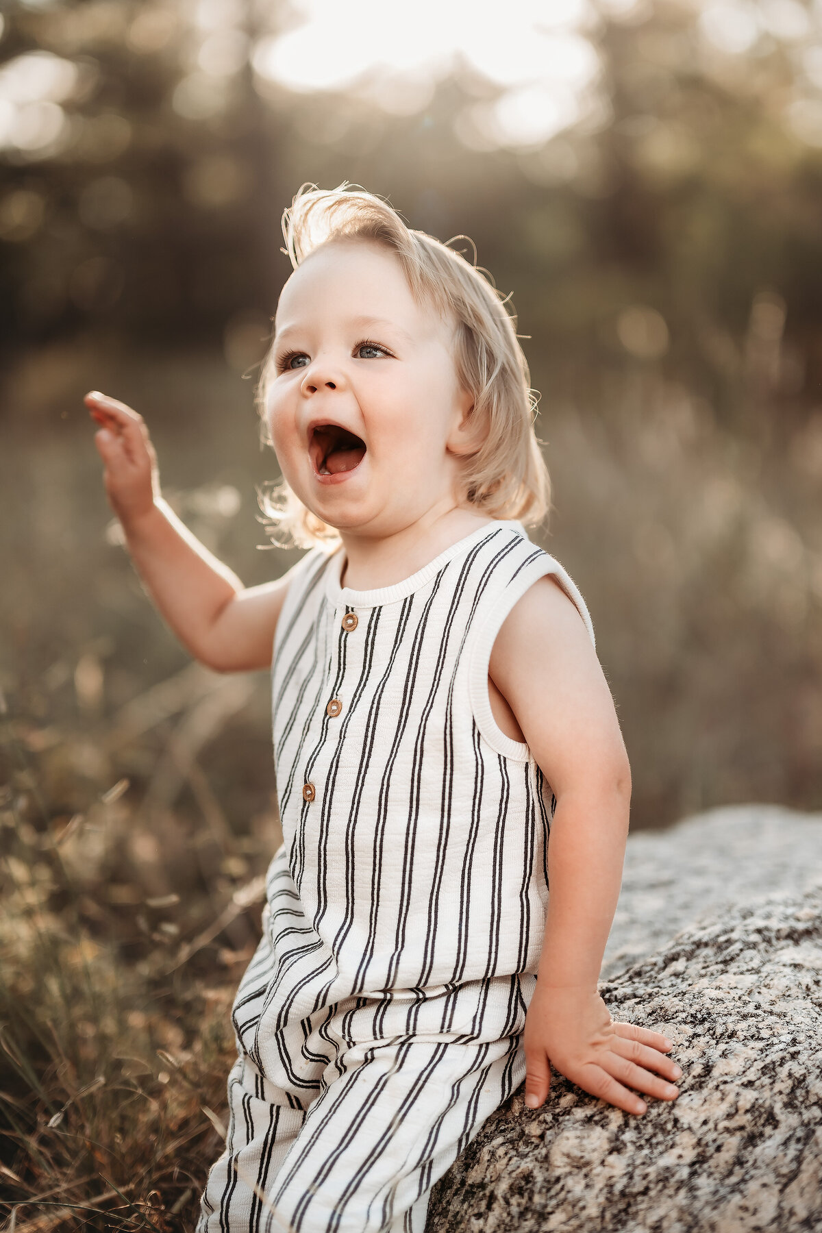 boy leaning on rock wearing striped romper