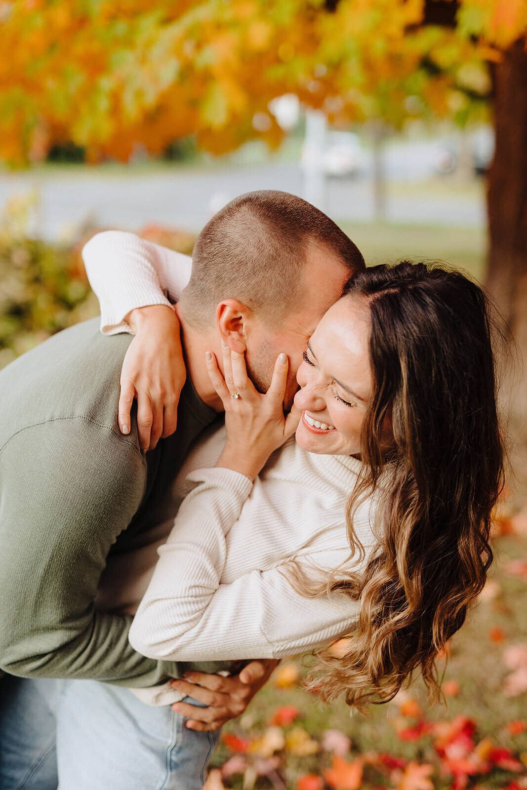 Couple hugging and laughing under an orange tree at Finger Lakes engagement session