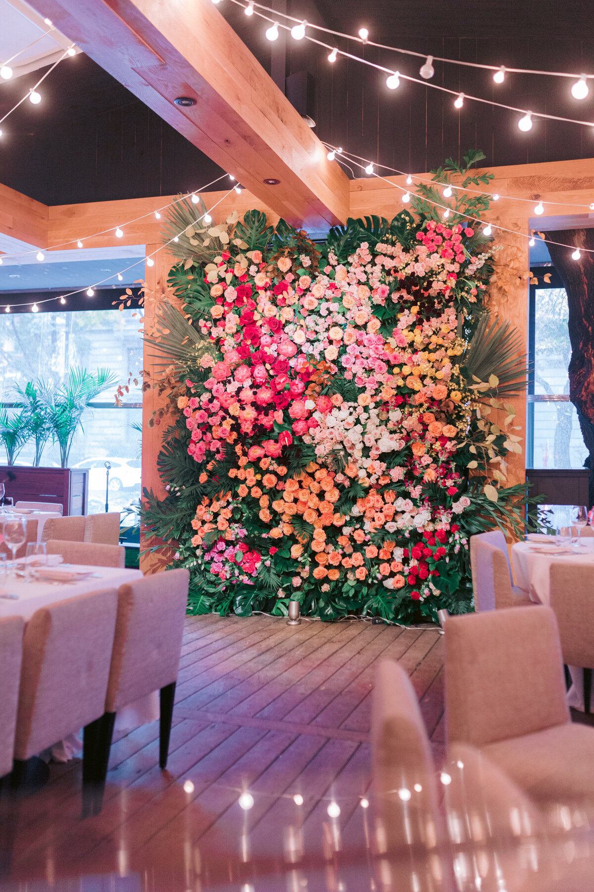 A wall installation of pink flowers and exotic greenery at a wedding ceremony at Restaurant Beatrice. 