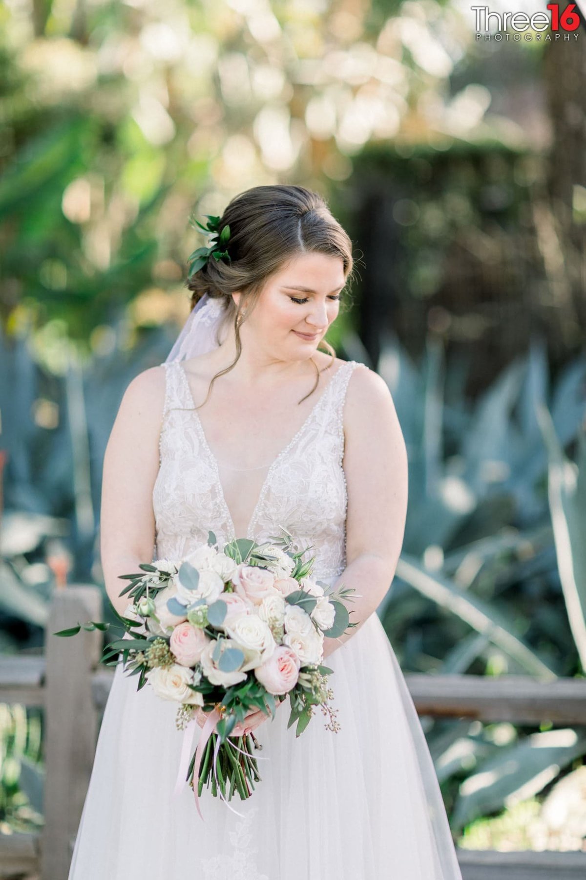 Bride looks down as she poses with her bouquet