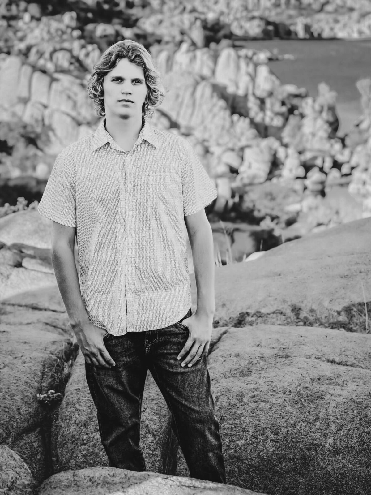 Young man poses on boulders at Watson Lake during Prescott senior photography session with Melissa Byrne
