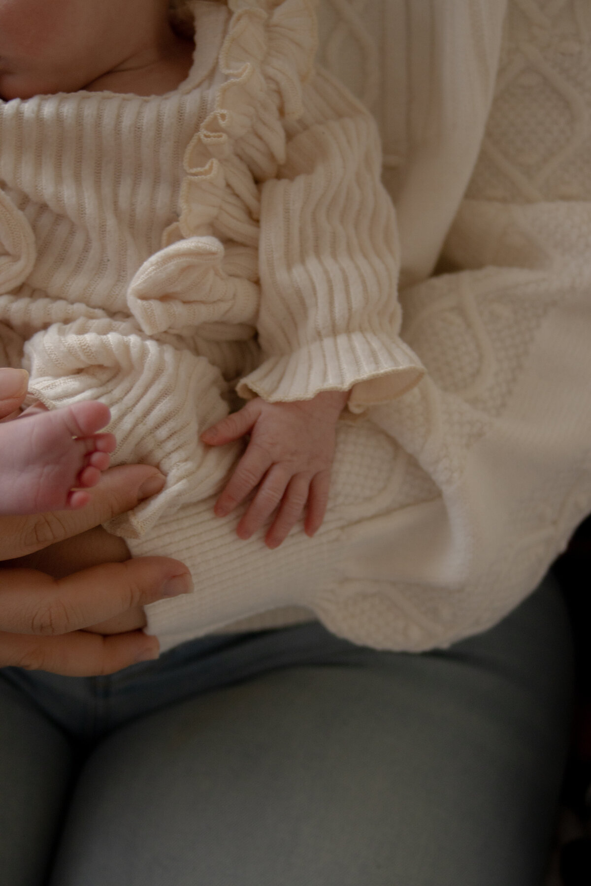 close up of tiny newborn hands and feet while being held of mom's chest during in-home lifestyle shoot