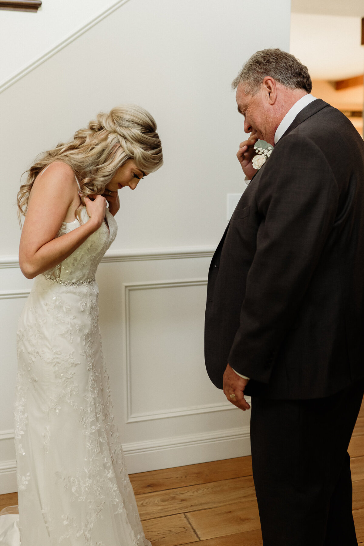 bride and father of the bride admire her gown during their first look